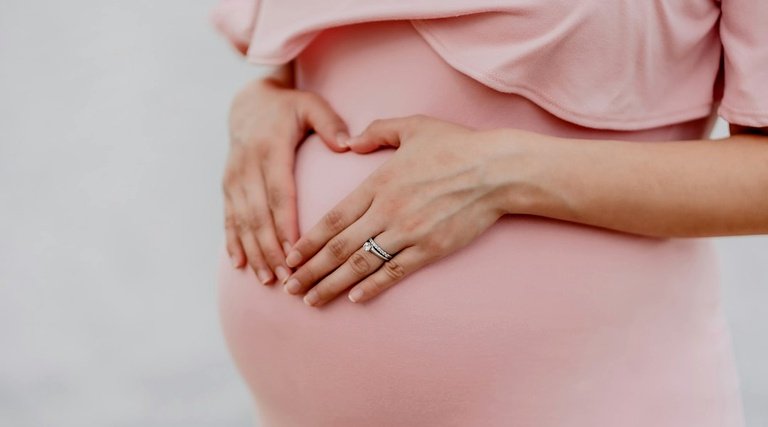 Gestante apoia mãos sobre a barriga enquanto aguarda direito ao salário-maternidade pelo INSS