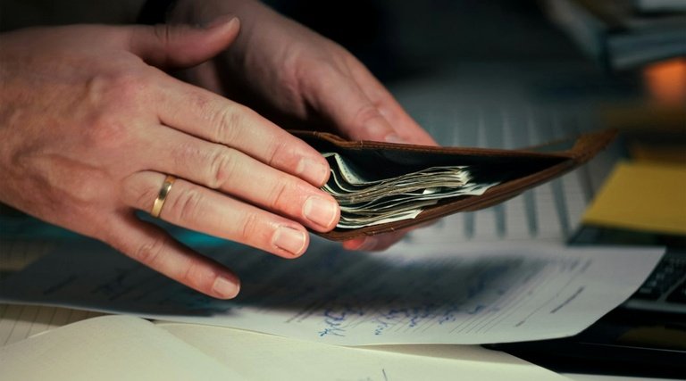Salário-maternidade para empregada com carteira assinada Salário-maternidade para empregada com carteira assinada: Mãos seguram carteira com cédulas sobre documentos relacionados