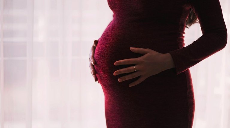 Salário-maternidade: Gestante apoia mãos sobre a barriga enquanto aguarda esclarecimentos sobre dúvidas frequentes