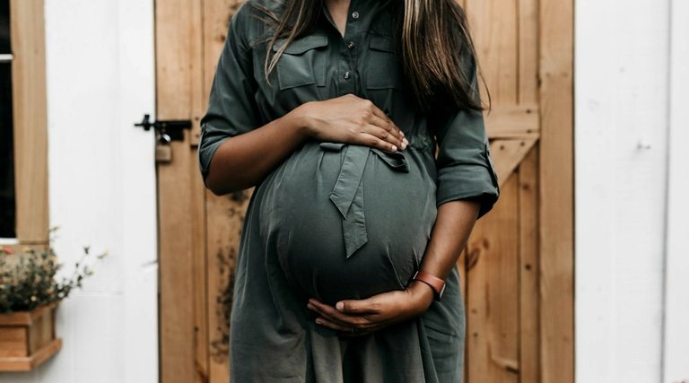 Salário-maternidade: Gestante posiciona mãos sobre barriga enquanto aguarda benefício previdenciário